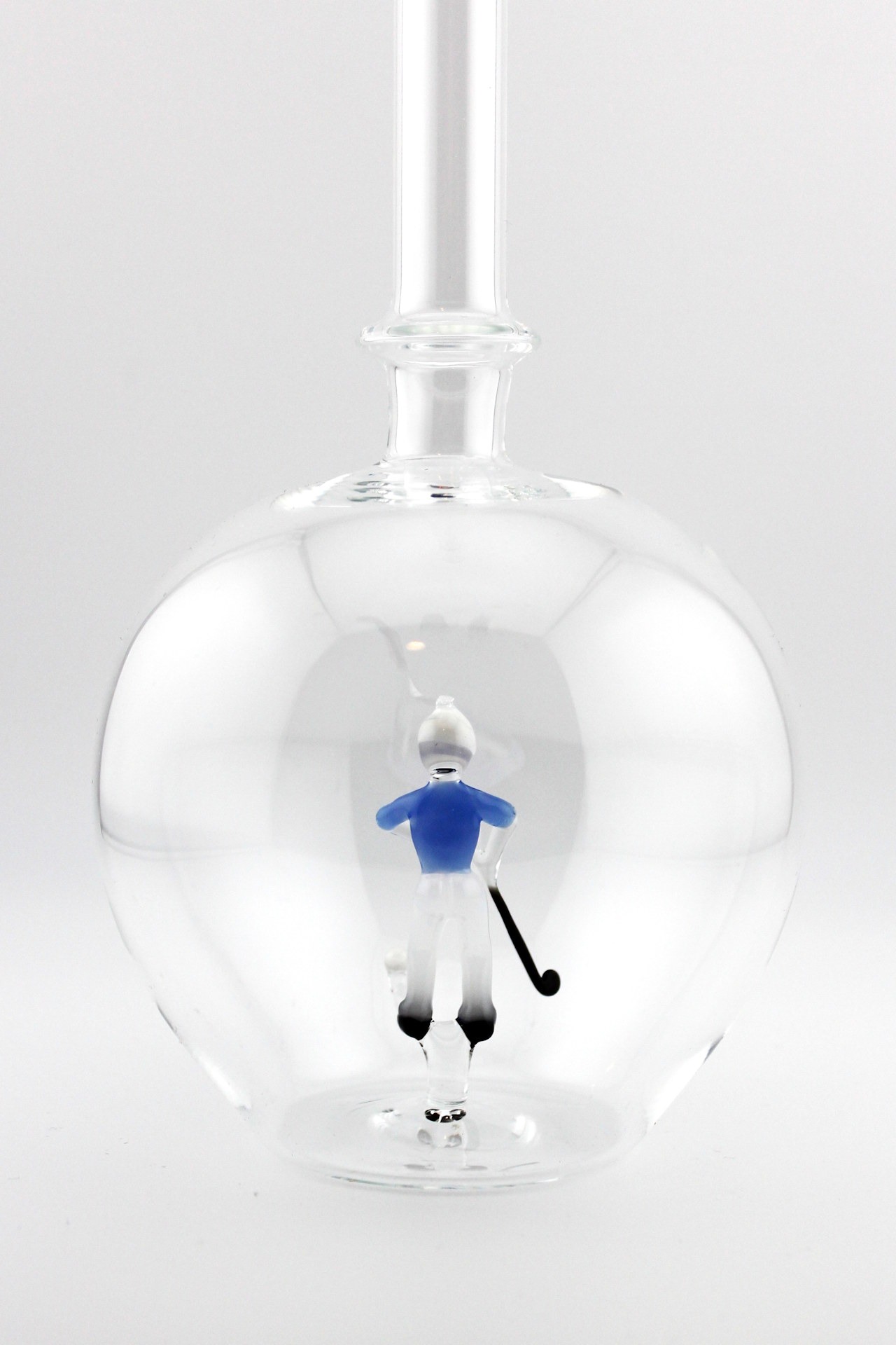 Eine leere bauchige Flasche aus Glas mit einem aus Glas geblasenen Golfspieler im Inneren.