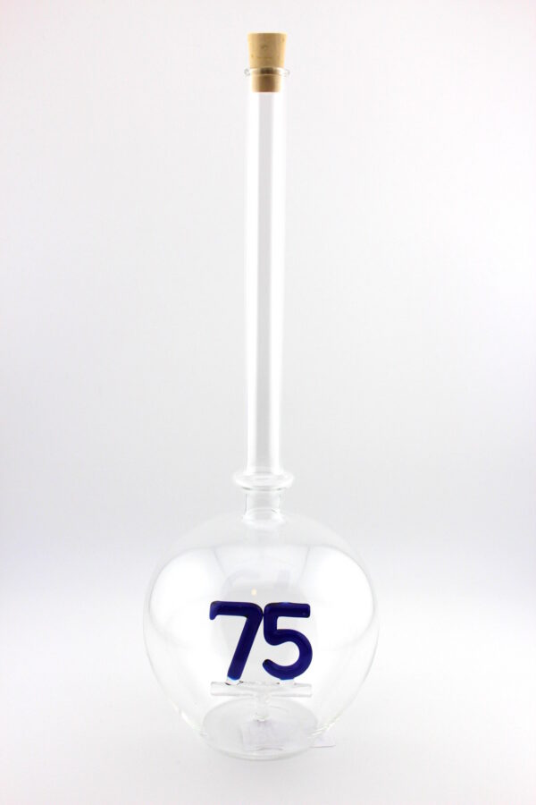 Eine leere bauchige Flasche aus Glas mit einer aus Glas geblasenen Zahl 75 im Inneren.