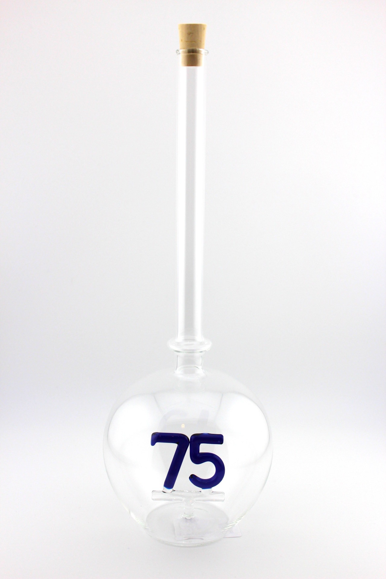 Eine leere bauchige Flasche aus Glas mit einer aus Glas geblasenen Zahl 75 im Inneren.
