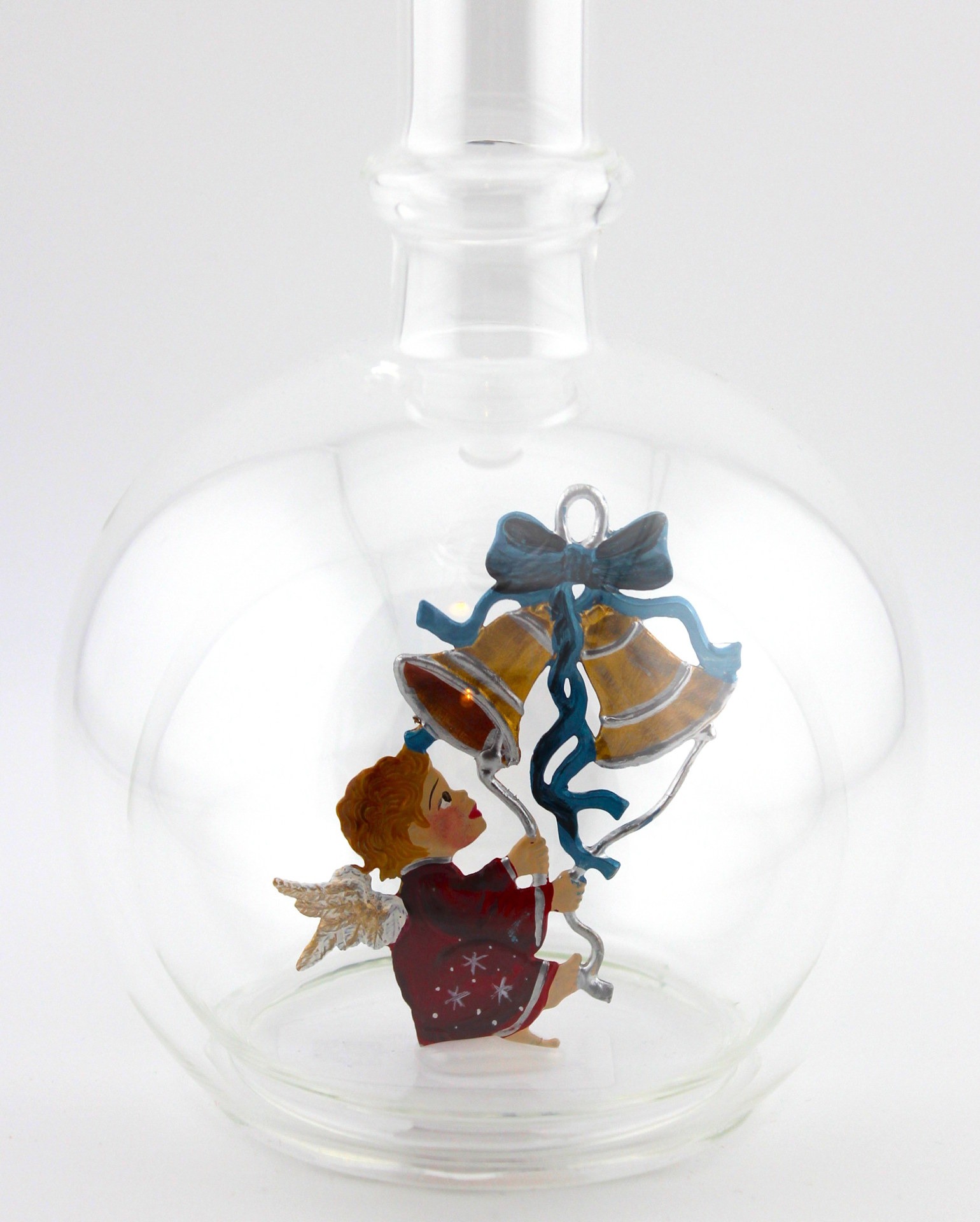 Eine leere bauchige Flasche aus Glas mit Weihnachtsläuten im Inneren.