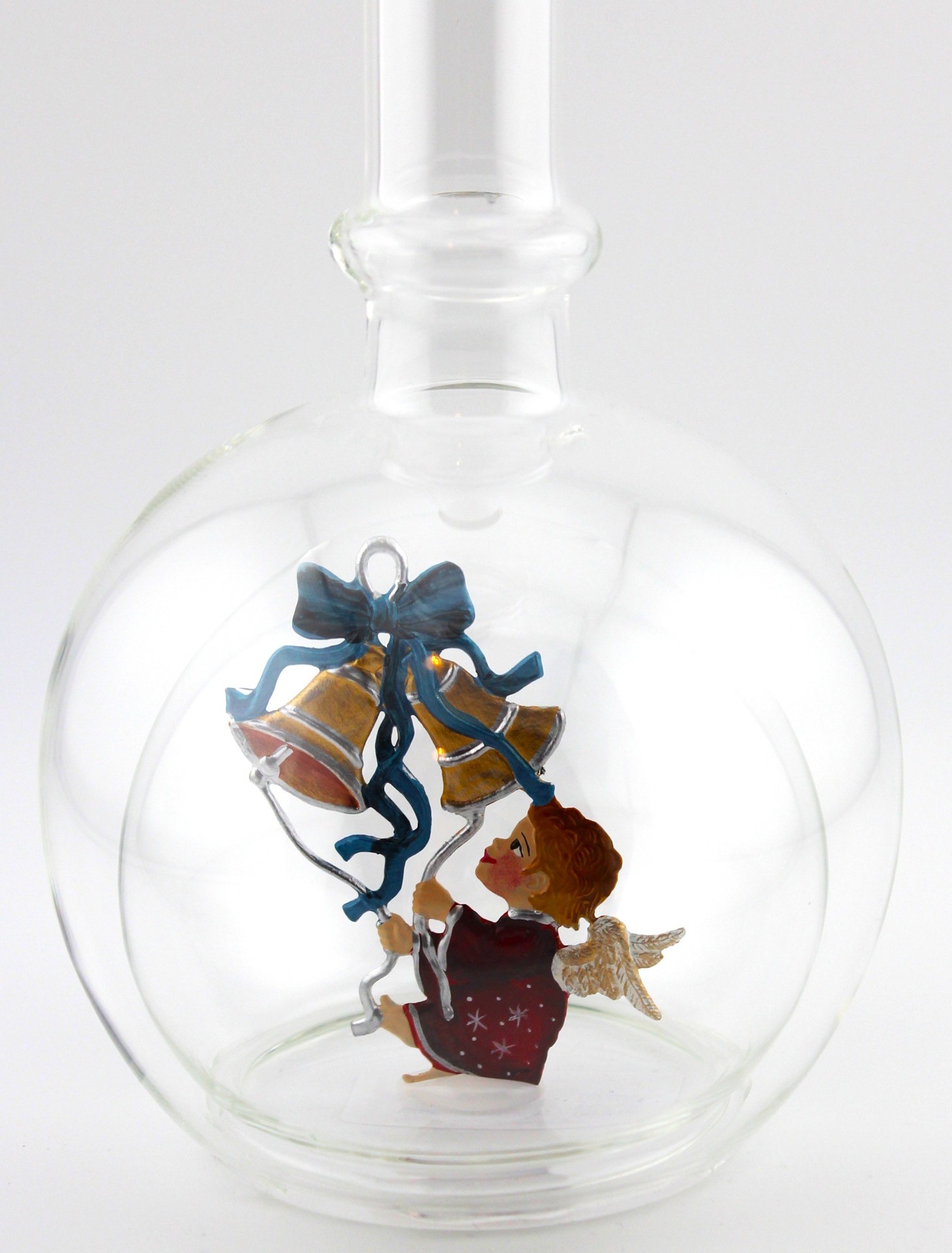 Eine leere bauchige Flasche aus Glas mit Weihnachtsläuten im Inneren.
