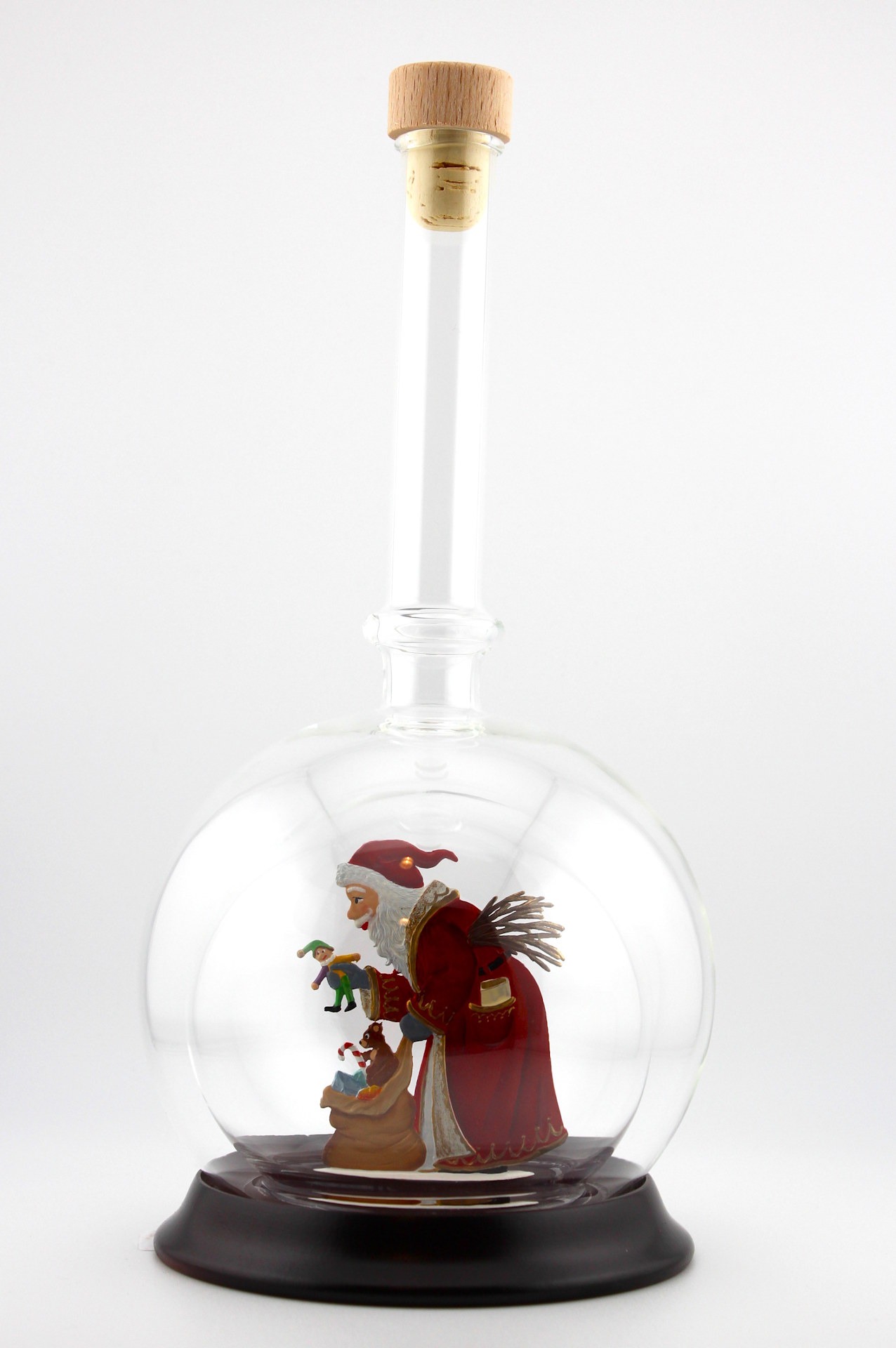 Eine leere bauchige Flasche aus Glas mit Weihnachtsmann mit Geschenkesack im Inneren.