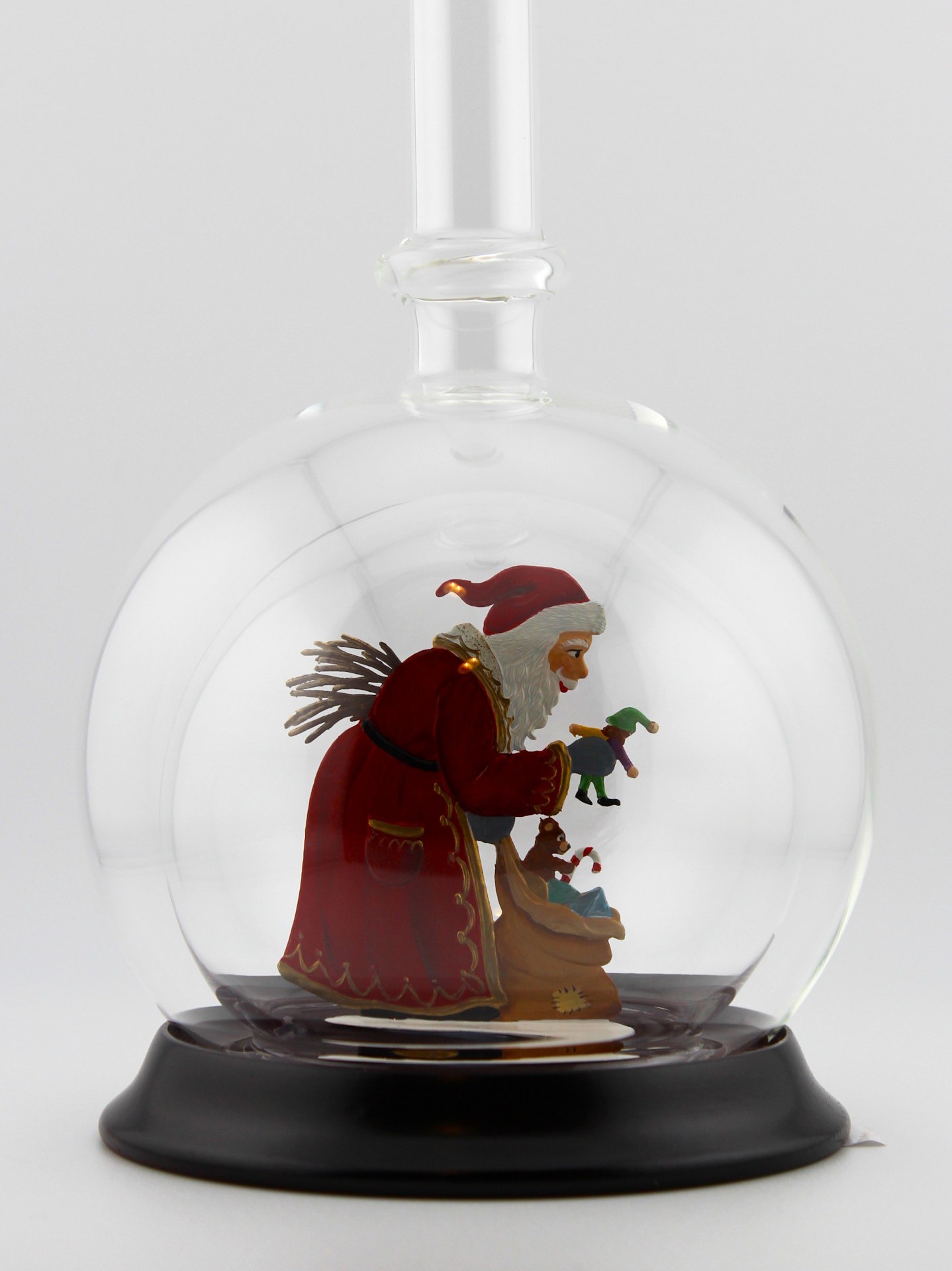 Eine leere bauchige Flasche aus Glas mit Weihnachtsmann mit Geschenkesack im Inneren.