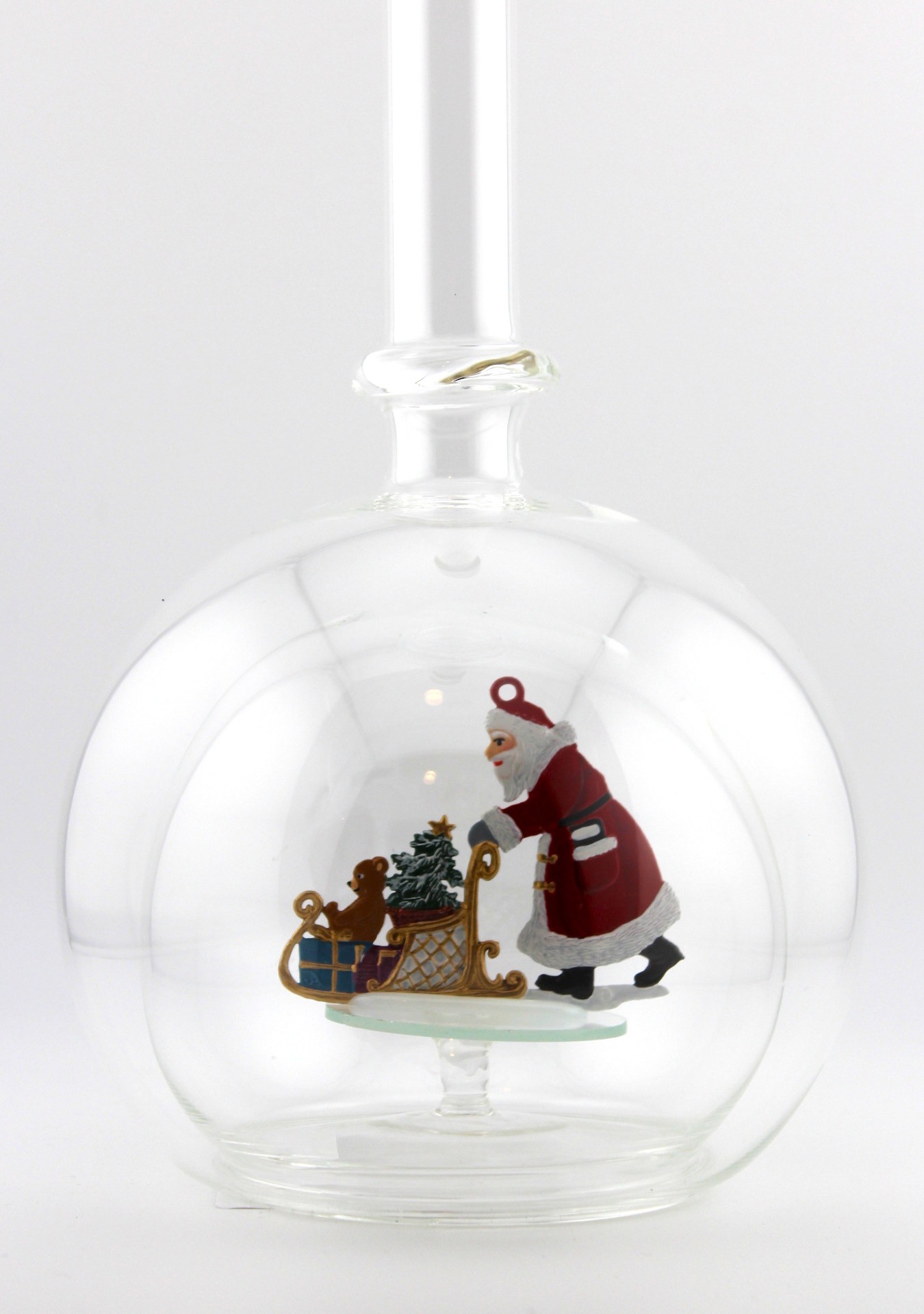 Eine leere bauchige Flasche aus Glas mit einem Schlitten schiebenden Weihnachtsmann im Inneren.