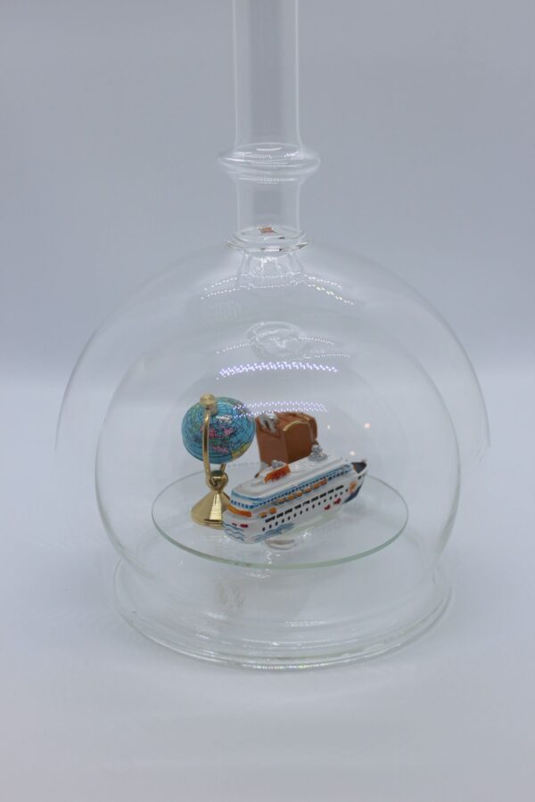 Eine leere bauchige Flasche aus Glas mit einem Kreuzfahrtschiff, Globus und Koffer im Inneren.