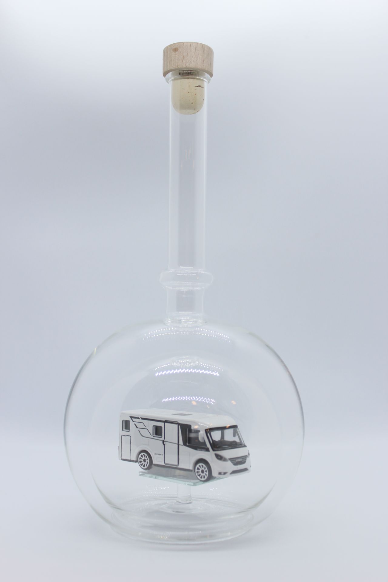 Eine leere bauchige Flasche aus Glas mit einem Wohnmobil im Inneren.