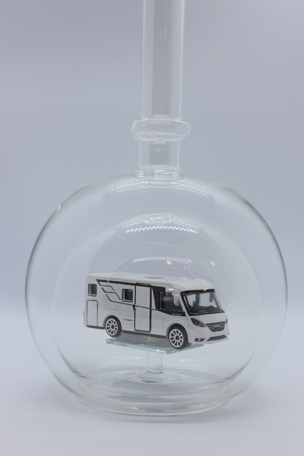 Eine leere bauchige Flasche aus Glas mit einem Wohnmobil im Inneren.