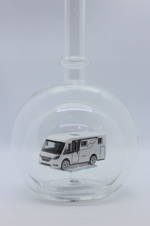 Eine leere bauchige Flasche aus Glas mit einem Wohnmobil im Inneren.