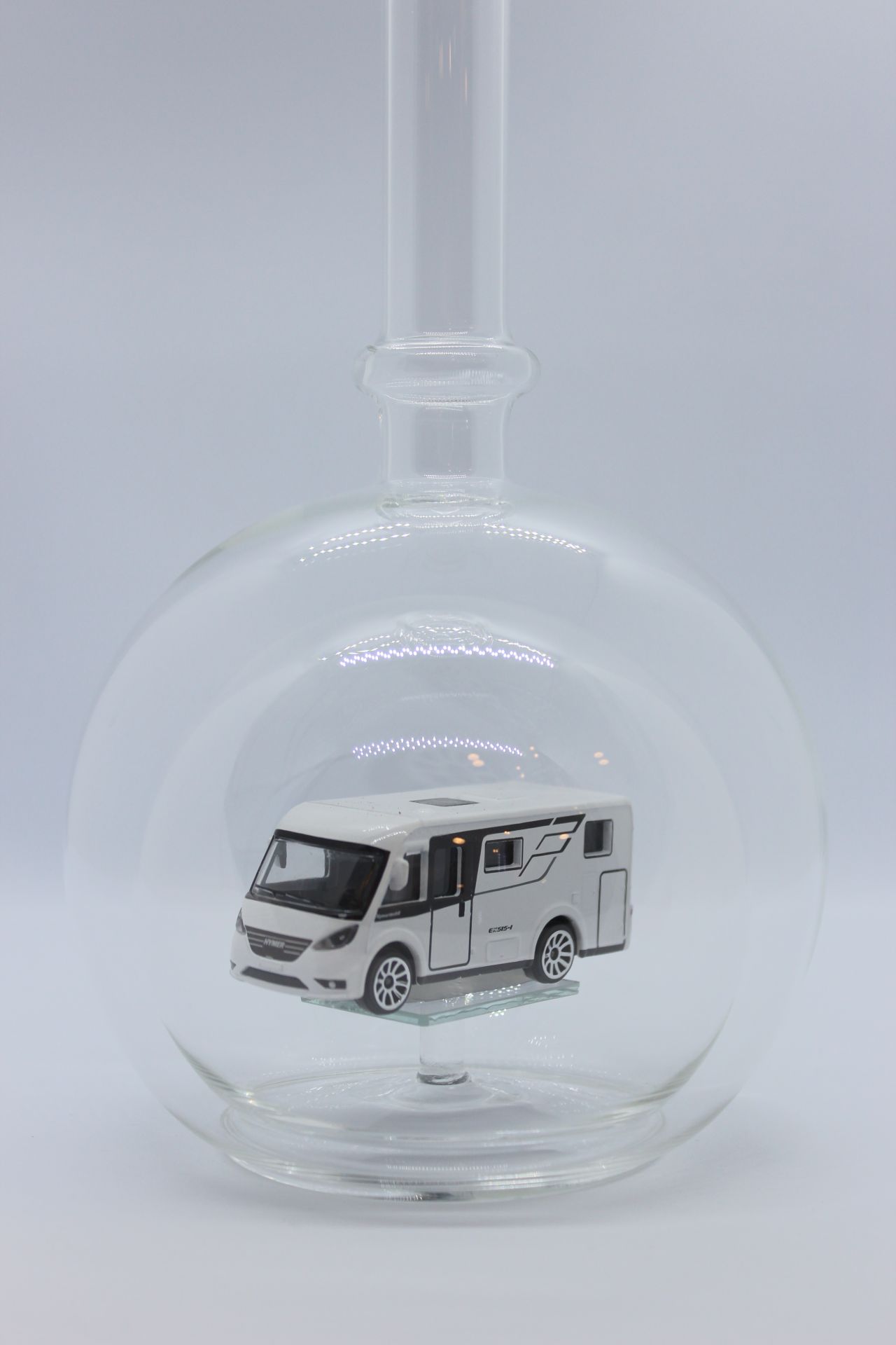 Eine leere bauchige Flasche aus Glas mit einem Wohnmobil im Inneren.