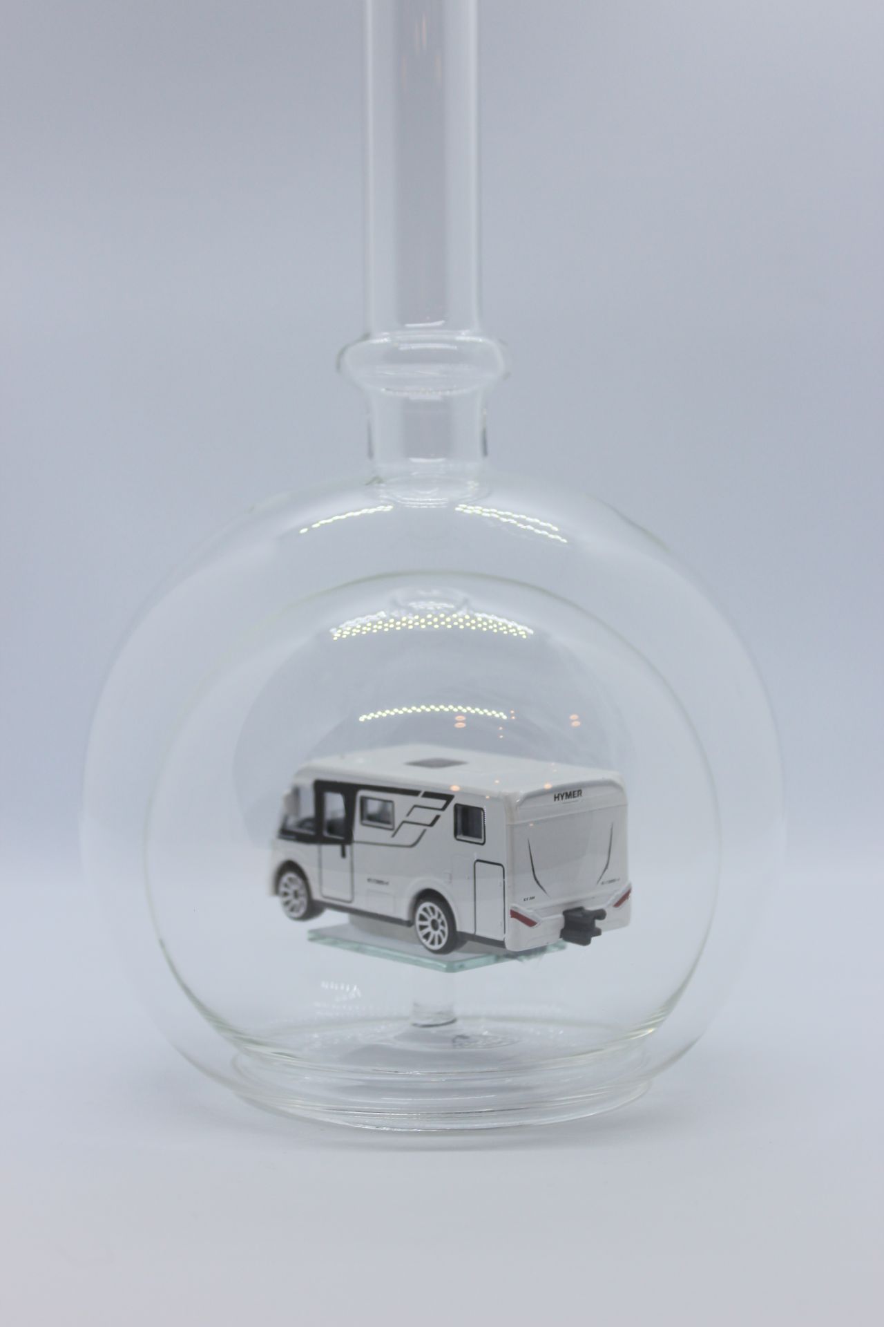 Eine leere bauchige Flasche aus Glas mit einem Wohnmobil im Inneren.
