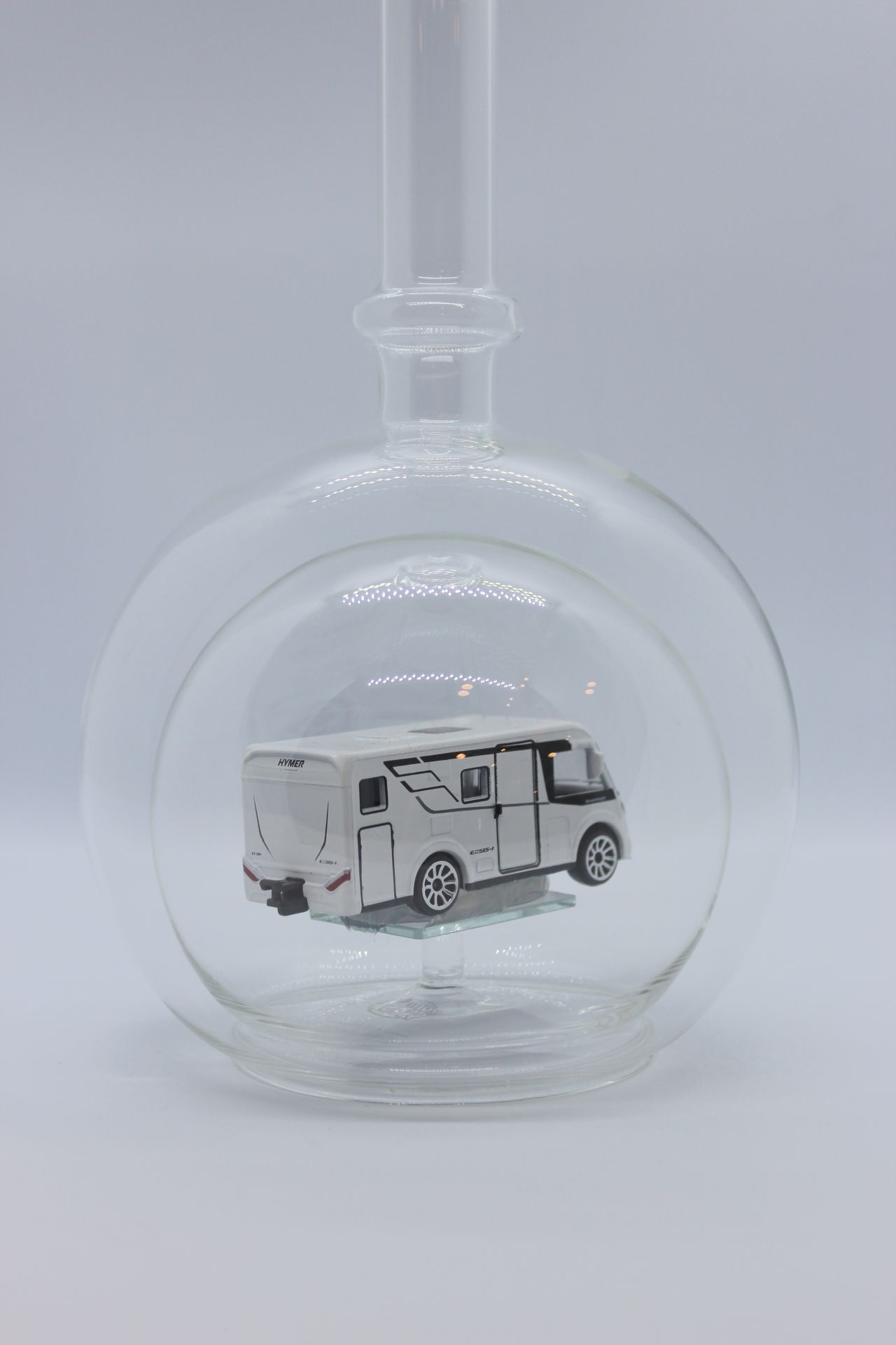 Eine leere bauchige Flasche aus Glas mit einem Wohnmobil im Inneren.