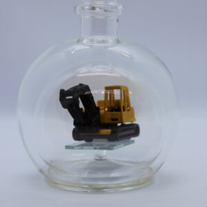 Eine leere bauchige Flasche aus Glas mit einem Bagger im Inneren.