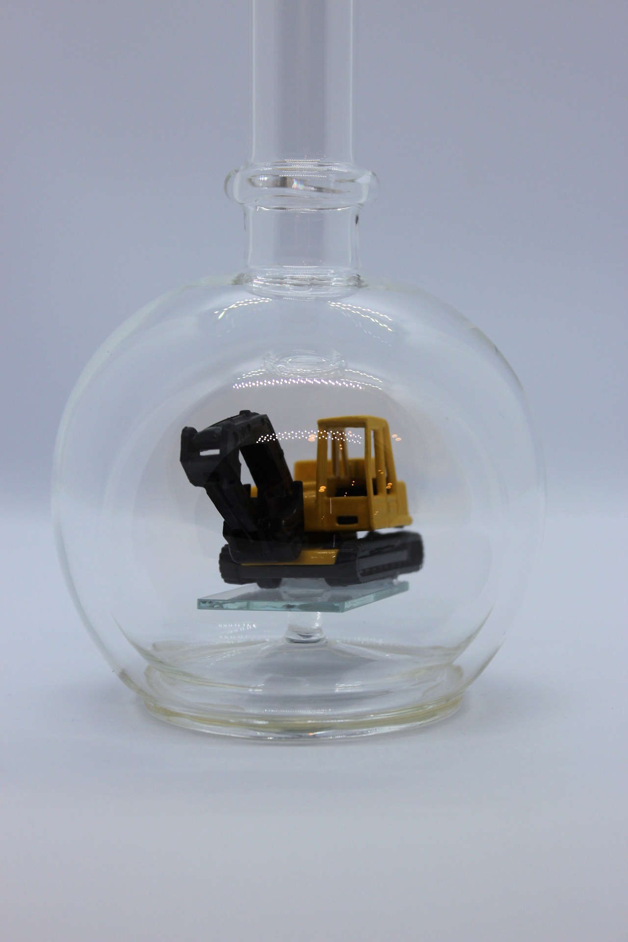 Eine leere bauchige Flasche aus Glas mit einem Bagger im Inneren.