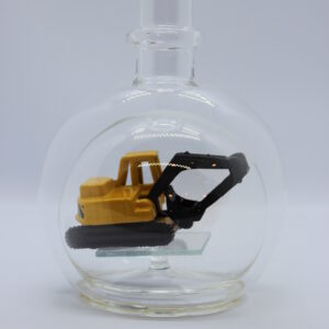 Eine leere bauchige Flasche aus Glas mit einem Bagger im Inneren.