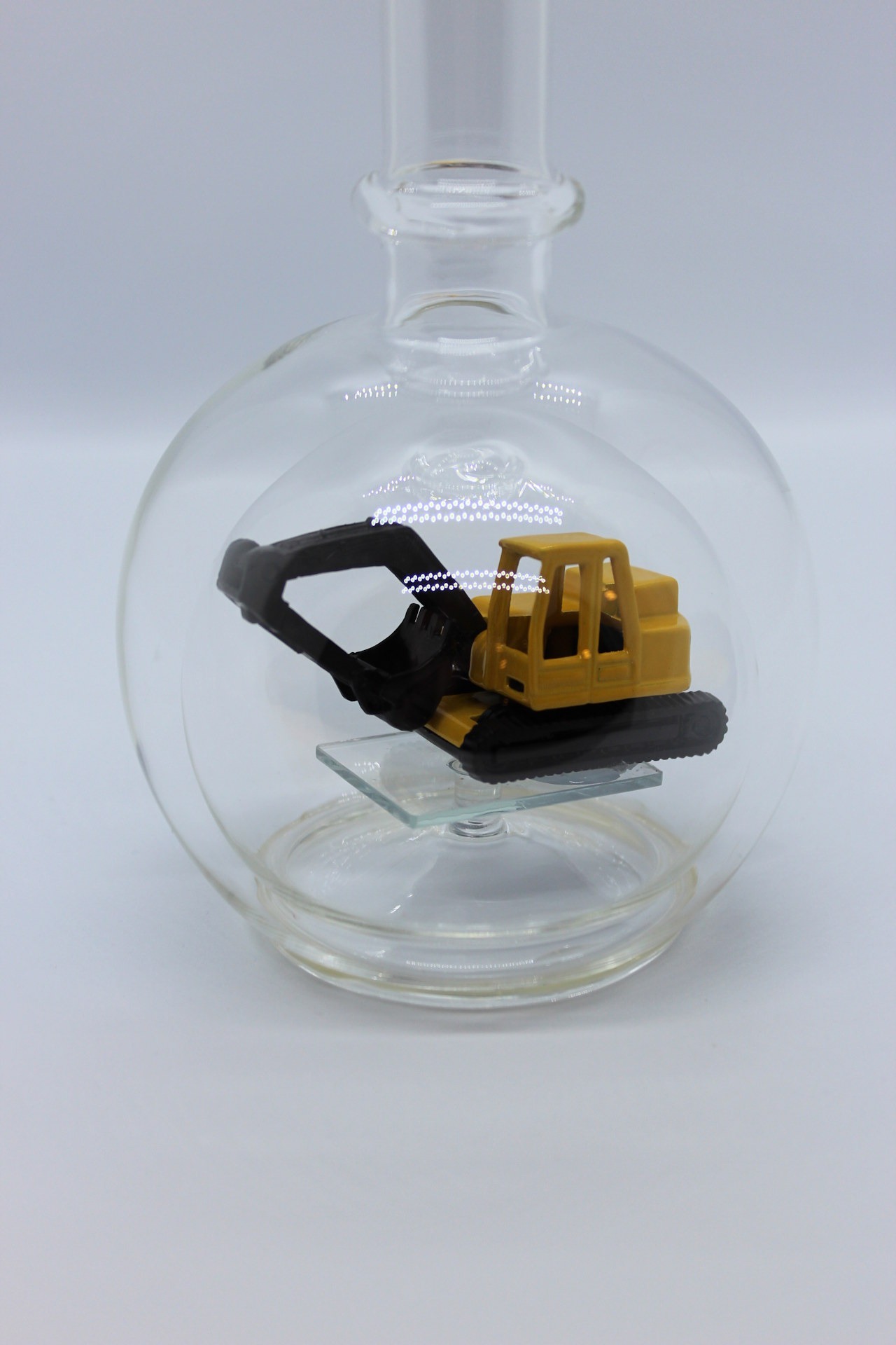 Eine leere bauchige Flasche aus Glas mit einem Bagger im Inneren.