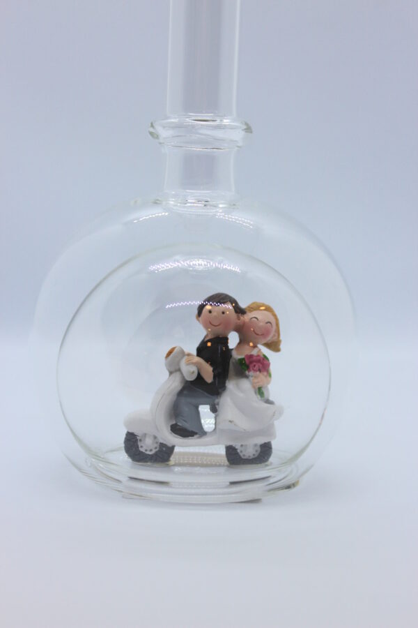 Eine leere bauchige Flasche aus Glas mit einem Brautpaar auf'm Mofa im Inneren.
