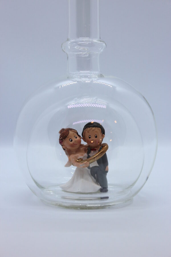 Eine leere bauchige Flasche aus Glas mit einem Brautpaar - gefangenem Bräutigam im Inneren.