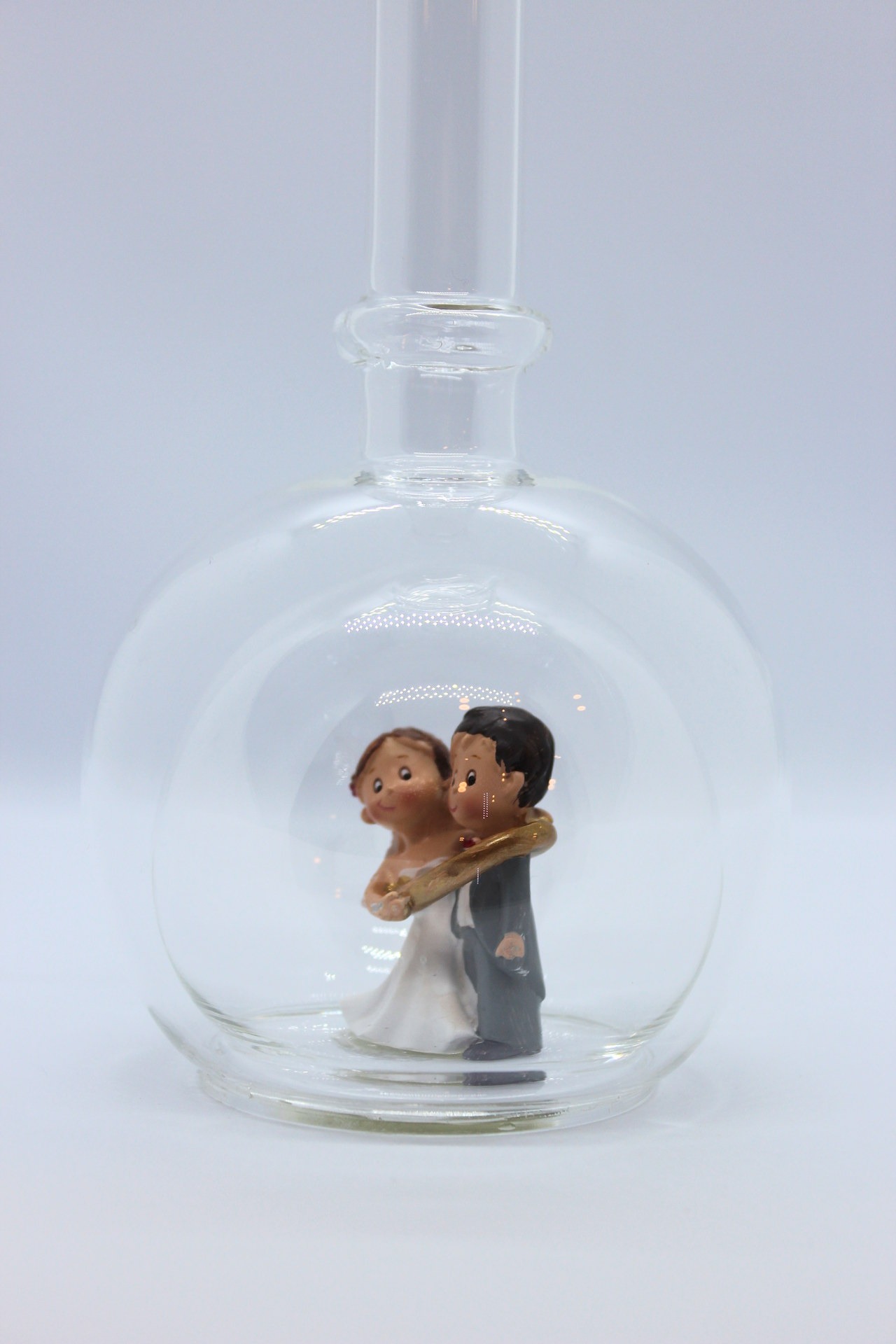 Eine leere bauchige Flasche aus Glas mit einem Brautpaar - gefangenem Bräutigam im Inneren.
