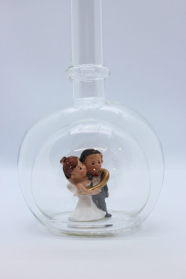 Eine leere bauchige Flasche aus Glas mit einem Brautpaar - gefangenem Bräutigam im Inneren.