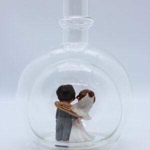 Eine leere bauchige Flasche aus Glas mit einem Brautpaar - gefangenem Bräutigam im Inneren.