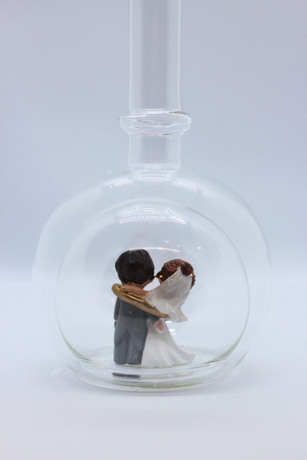 Eine leere bauchige Flasche aus Glas mit einem Brautpaar - gefangenem Bräutigam im Inneren.