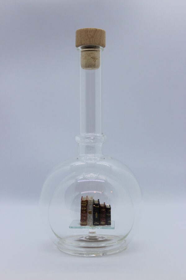 Eine leere bauchige Flasche aus Glas mit Büchern im Inneren.