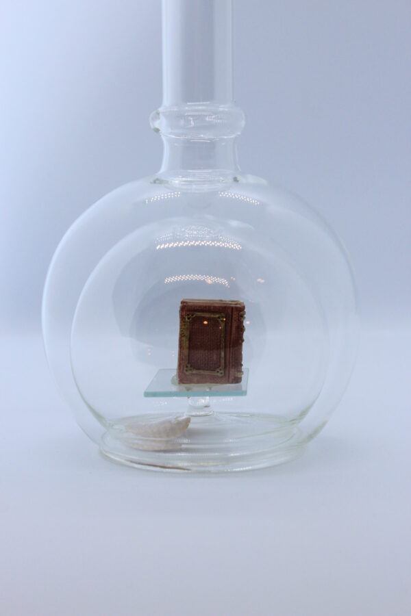 Eine leere bauchige Flasche aus Glas mit Büchern im Inneren.