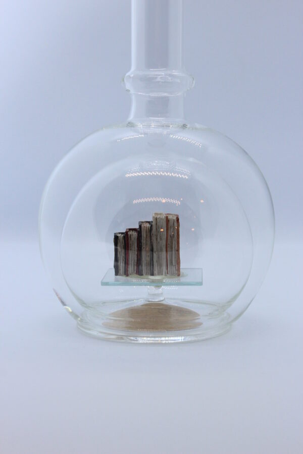 Eine leere bauchige Flasche aus Glas mit Büchern im Inneren.