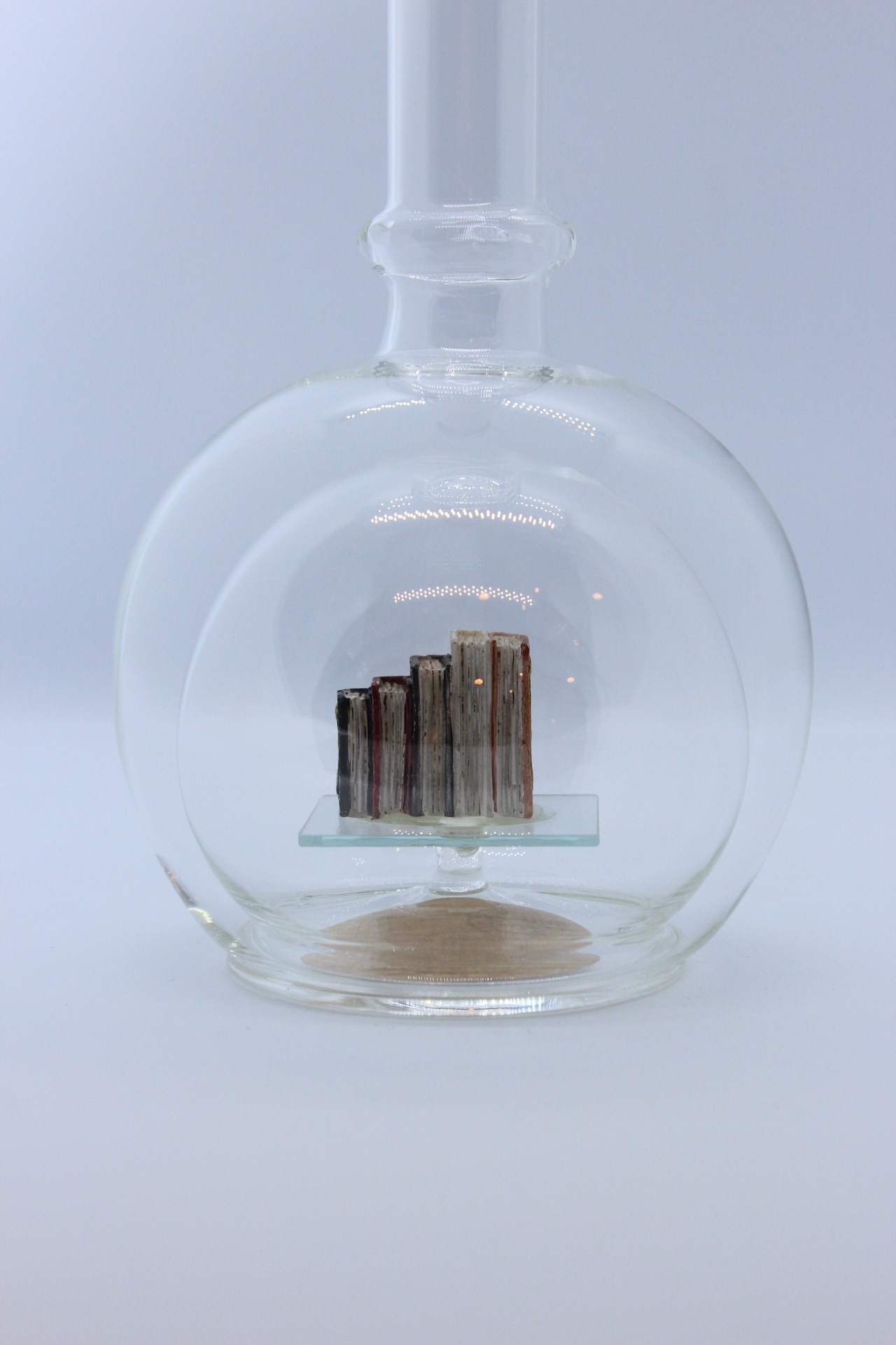 Eine leere bauchige Flasche aus Glas mit Büchern im Inneren.