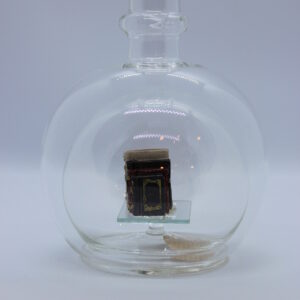 Eine leere bauchige Flasche aus Glas mit Büchern im Inneren.