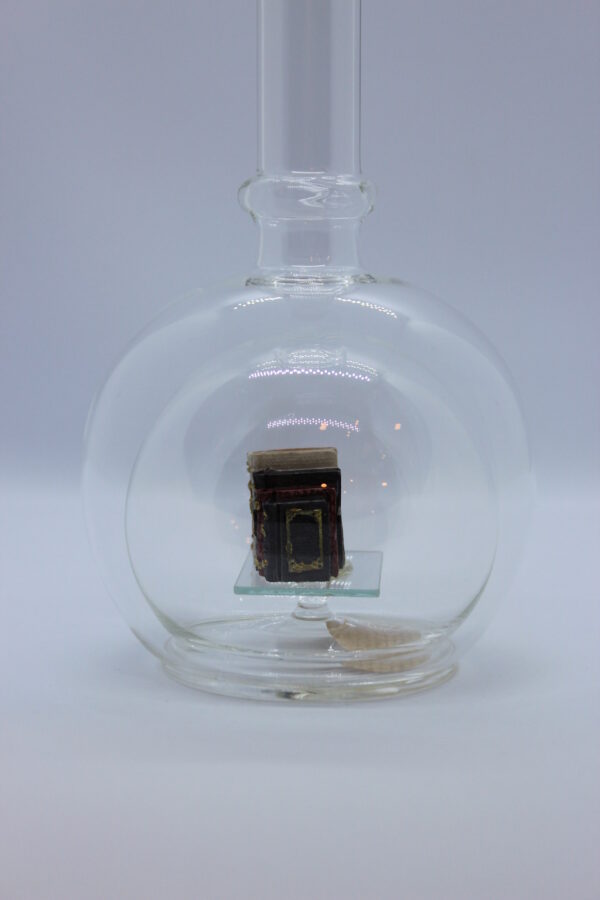 Eine leere bauchige Flasche aus Glas mit Büchern im Inneren.