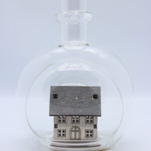 Eine leere bauchige Flasche aus Glas mit einem Haus / Eigenheim im Inneren.