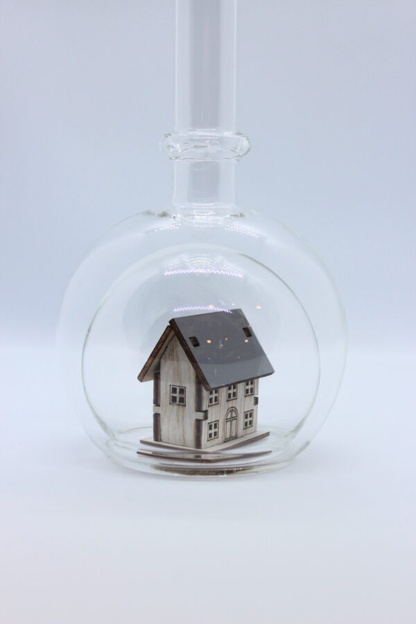 Eine leere bauchige Flasche aus Glas mit einem Haus / Eigenheim im Inneren.
