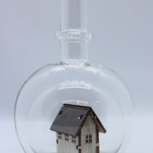 Eine leere bauchige Flasche aus Glas mit einem Haus / Eigenheim im Inneren.