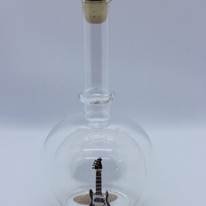 Eine leere bauchige Flasche aus Glas mit einer E-Gitarre im Inneren.