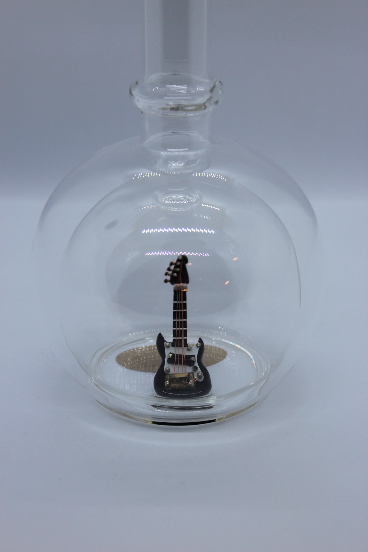 Eine leere bauchige Flasche aus Glas mit einer E-Gitarre im Inneren.