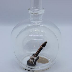Eine leere bauchige Flasche aus Glas mit einer E-Gitarre im Inneren.