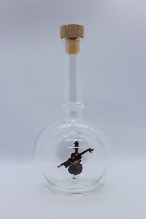 Eine leere bauchige Flasche aus Glas mit einer Geige im Inneren.