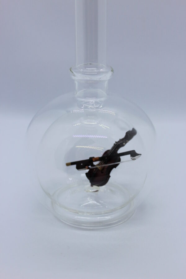 Eine leere bauchige Flasche aus Glas mit einer Geige im Inneren.