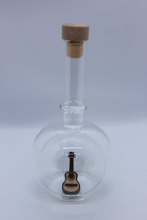 Eine leere bauchige Flasche aus Glas mit einer Gitarre im Inneren.