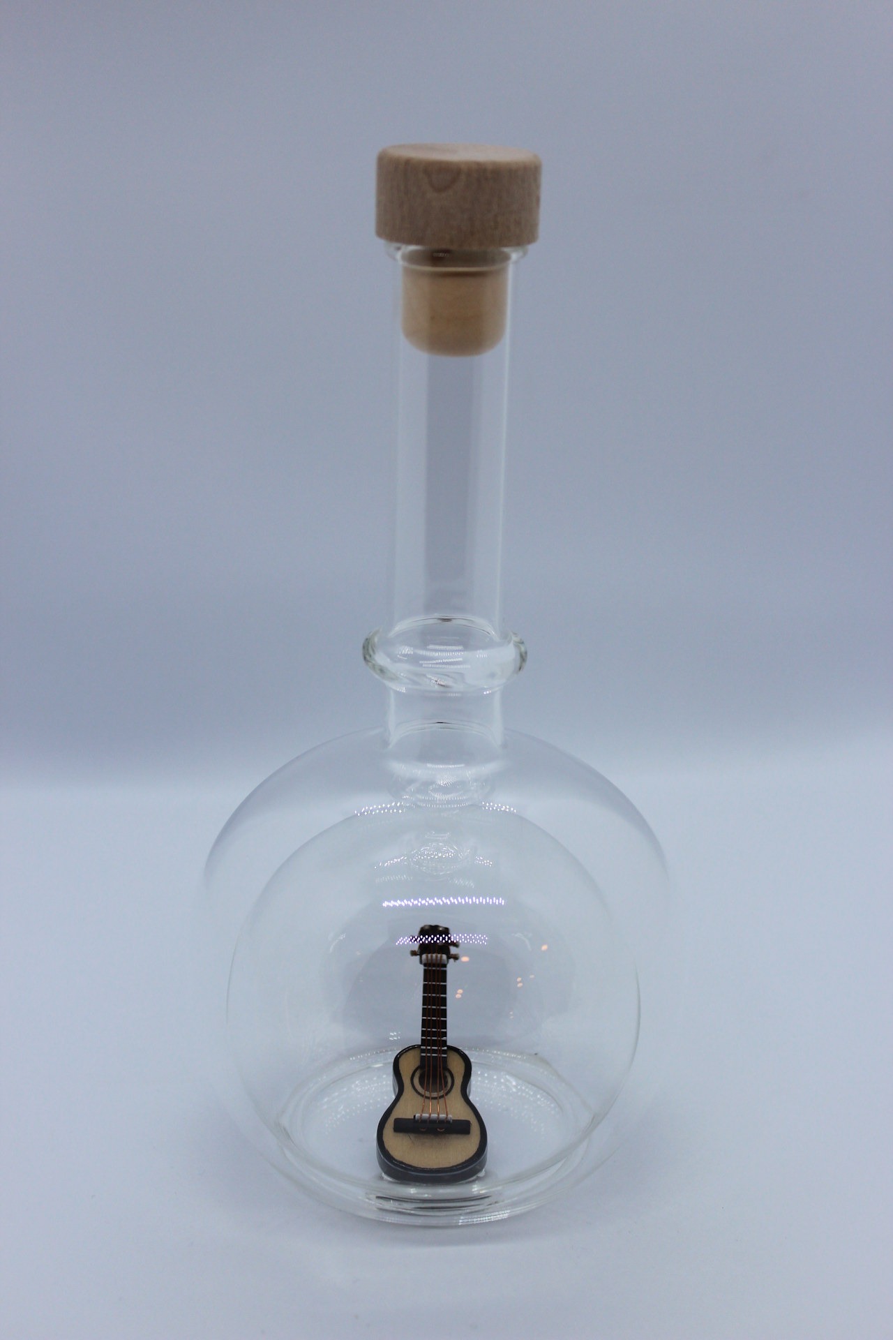 Eine leere bauchige Flasche aus Glas mit einer Gitarre im Inneren.