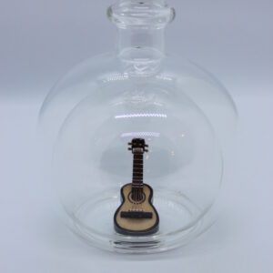 Eine leere bauchige Flasche aus Glas mit einer Gitarre im Inneren.