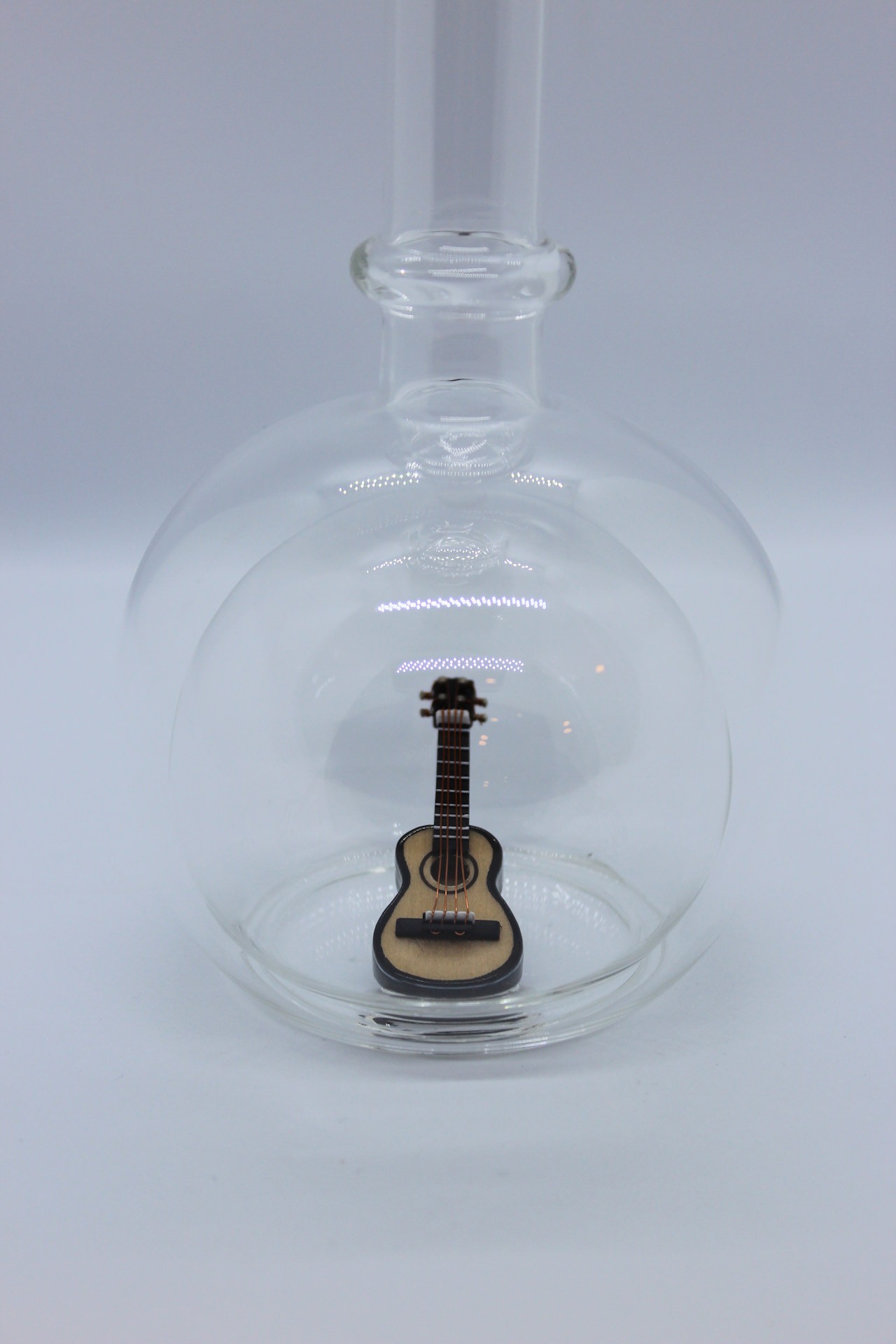 Eine leere bauchige Flasche aus Glas mit einer Gitarre im Inneren.