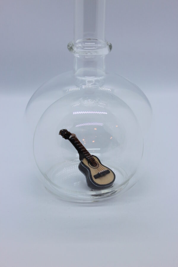 Eine leere bauchige Flasche aus Glas mit einer Gitarre im Inneren.