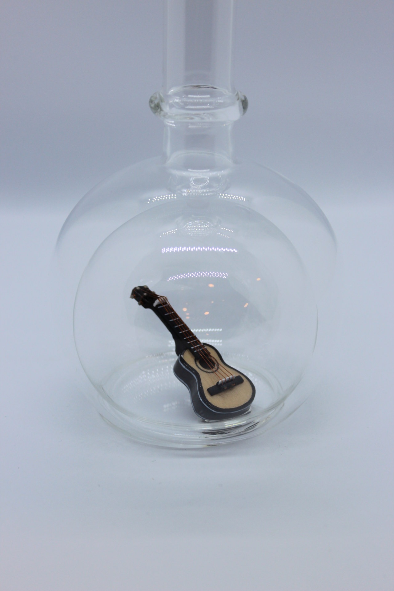 Eine leere bauchige Flasche aus Glas mit einer Gitarre im Inneren.