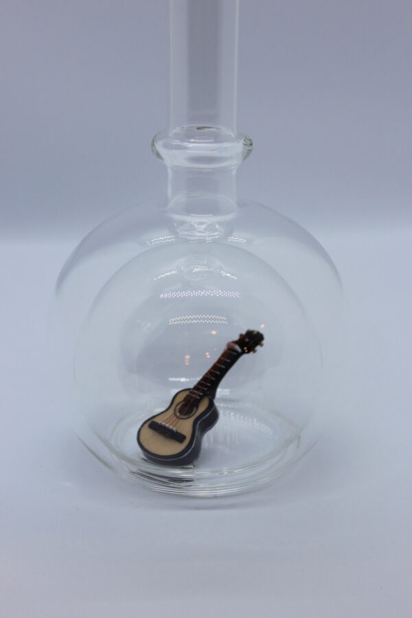 Eine leere bauchige Flasche aus Glas mit einer Gitarre im Inneren.