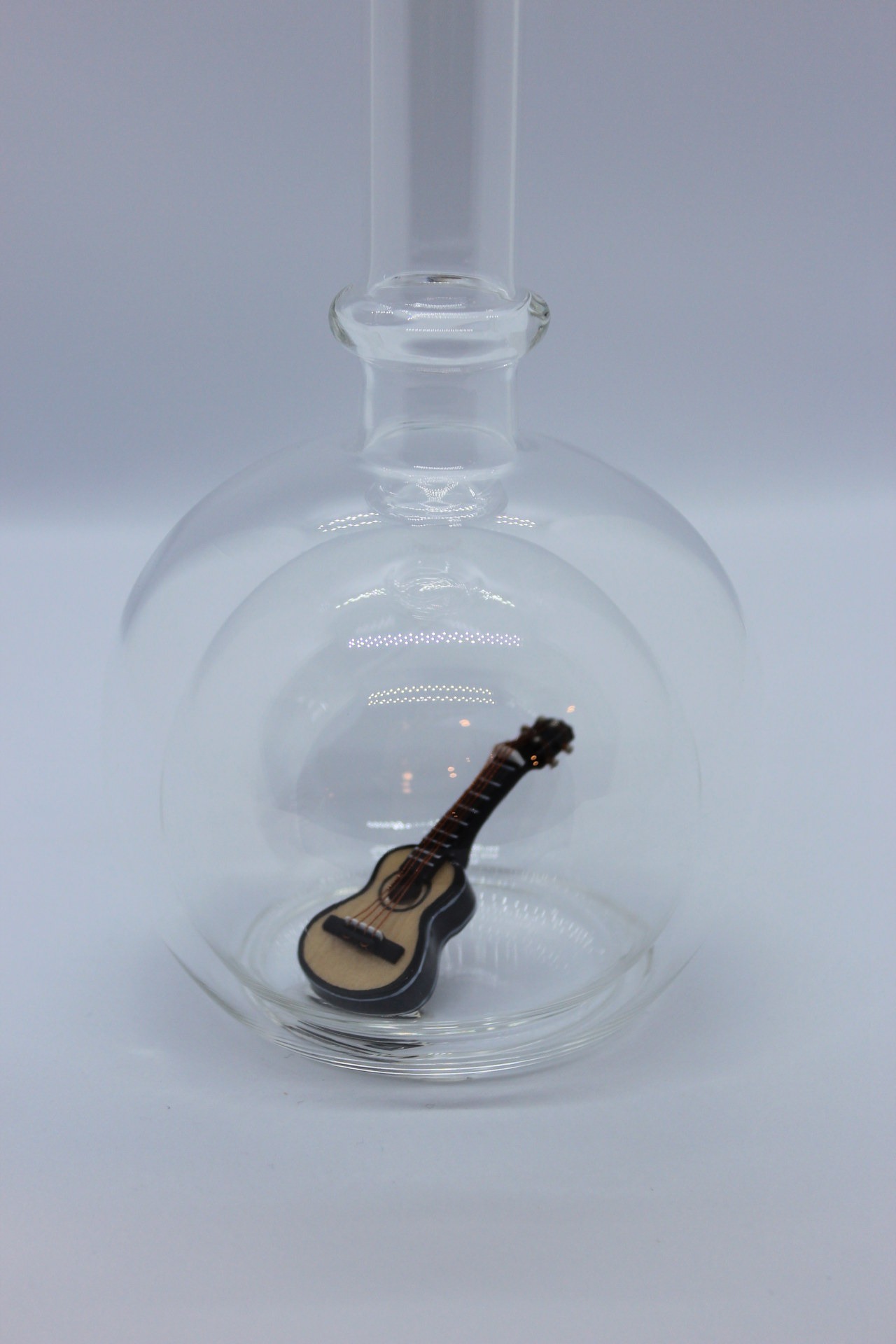 Eine leere bauchige Flasche aus Glas mit einer Gitarre im Inneren.