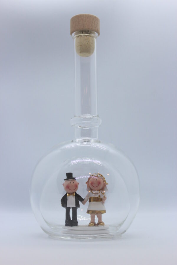 Eine leere bauchige Flasche aus Glas mit einem Goldenen Hochzeitspaar im Inneren.
