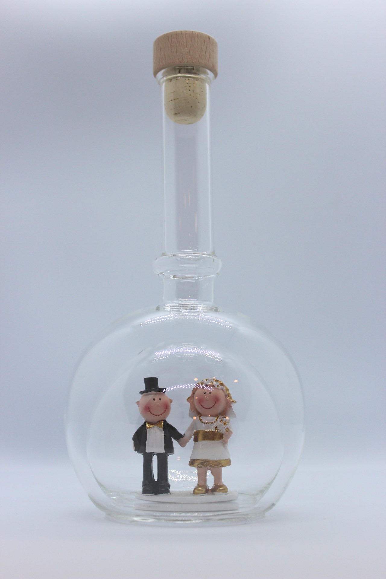Eine leere bauchige Flasche aus Glas mit einem Goldenen Hochzeitspaar im Inneren.