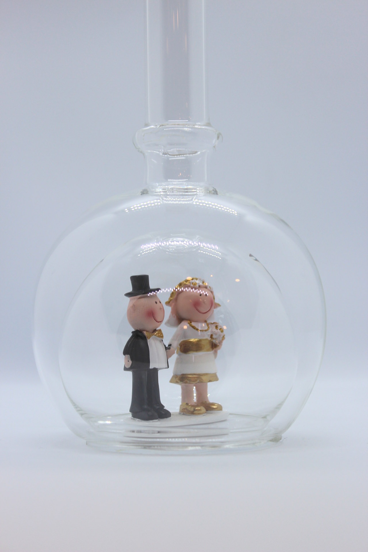 Eine leere bauchige Flasche aus Glas mit einem Goldenen Hochzeitspaar im Inneren.
